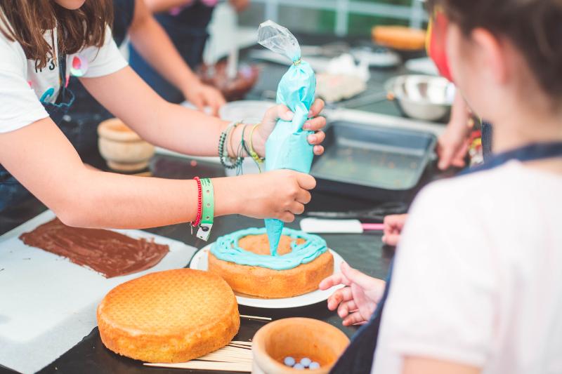 Grupo de niños en el campamento de Navidad haciendo dulces y repostería creativa navideña