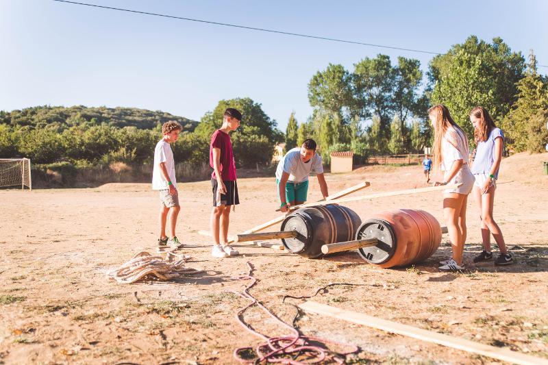 Grupo de niños participando en las carreras de los kart a pedales en la naturaleza del campamento de verano en Tarragona