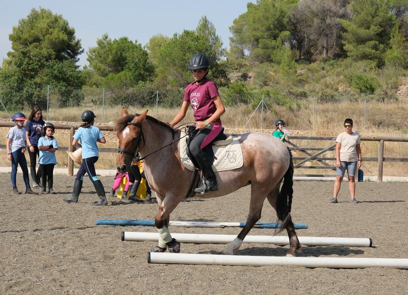 Niña participando en una competición hípica en el campamento de verano en Tarragona