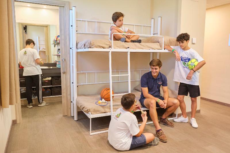 niños sentados en la litera de la habitacion del campamento de verano en tarragona