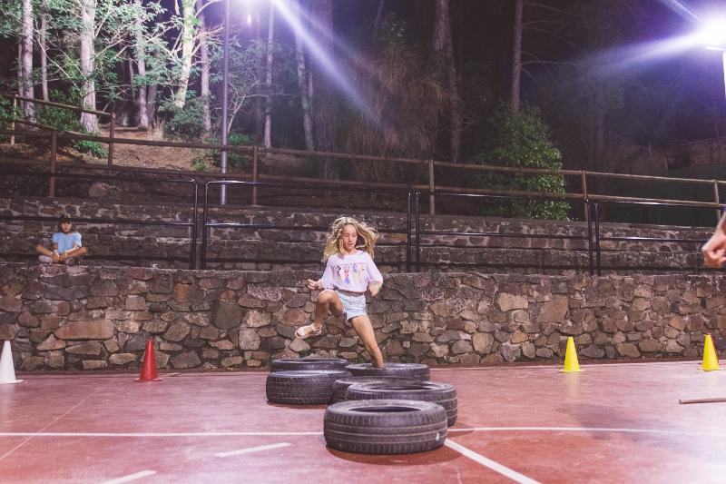 niña pasando las pruebas de un juego de competicion en el campamento de verano en tarragona