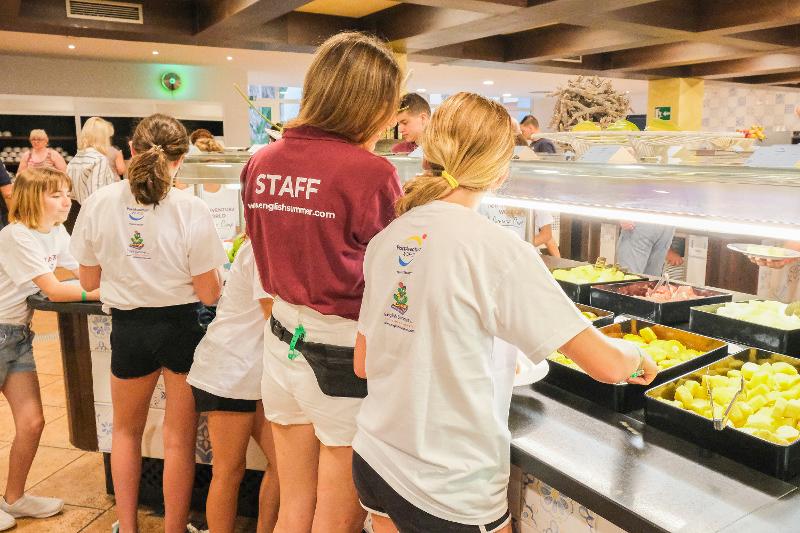 Grupo de niñas sirviéndose comida en el comedor del campamento de verano en Cataluña
