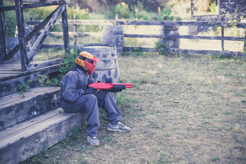Niño escondido preparado para atacar en el juego de paintball en el campamento de verano en tarragona