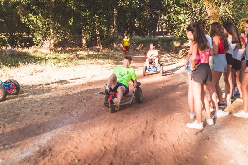 Grupo de niños participando en las carreras de los kart a pedales en la naturaleza del campamento de verano en tarragona