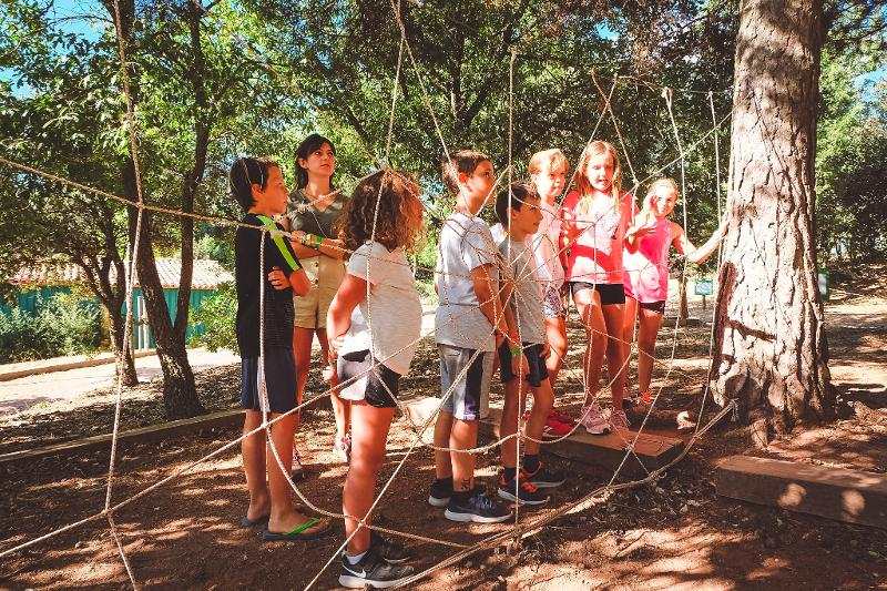 grupo de jóvenes intentando pasar la prueba de un juego en la naturaleza del campamento de aventura