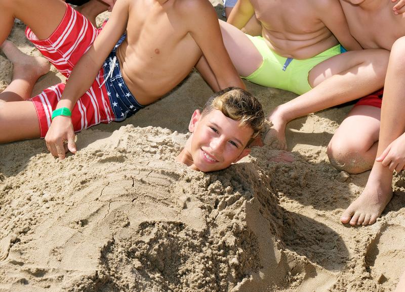 Niño enterrado con arena en la playa por sus compañeros del campamento de verano en tarragona