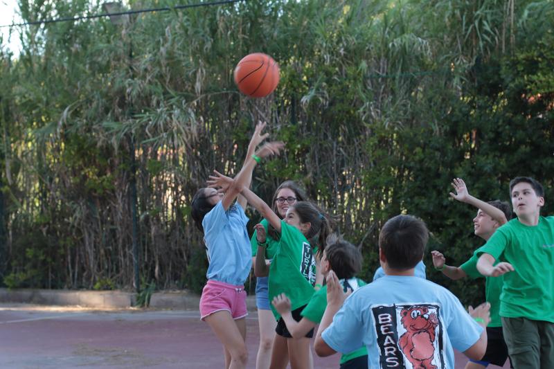 Grupo de niños jugando un partido de baloncesto e intentando meter una canasta en el campamento deportivo en tarragona