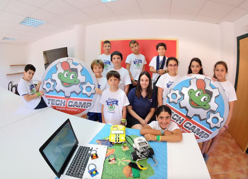 Grupo de jóvenes posando divertidos en el aula del campamento tecnológico