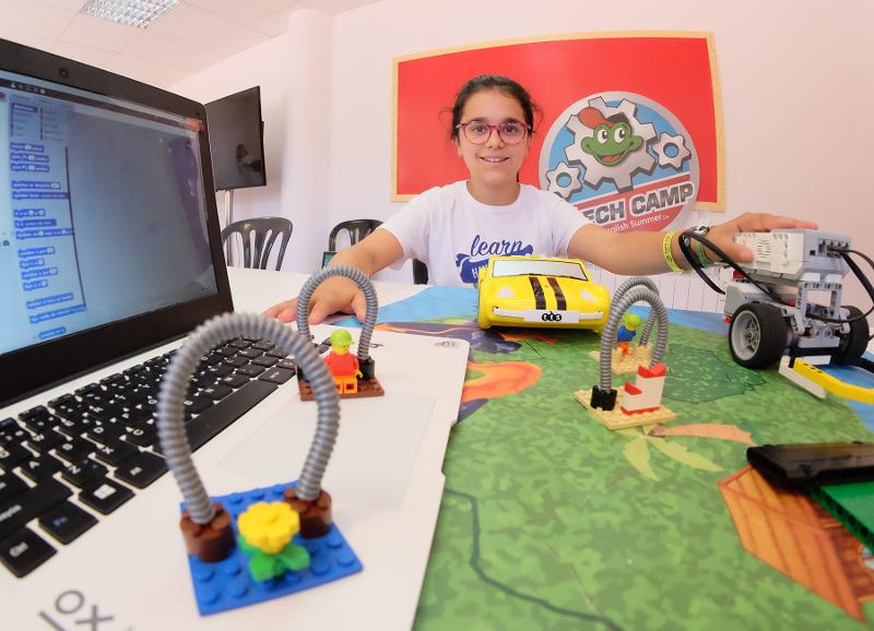 Niña contenta sujetando un robot hecho por ella durante el taller de programación del campamento científico