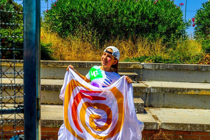 niña posando con una bandera en plena naturaleza del campamento de verano en Toledo