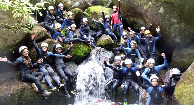 grupo de jovenes posando con los kayak en el rio del campamento de verano en portugal