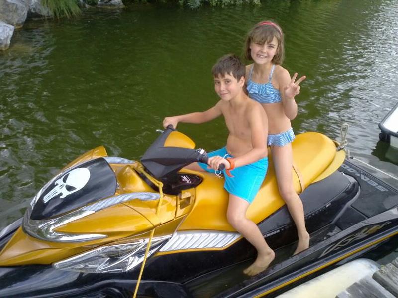 Pareja de niños montados en una moto acuática en el campamento de ingles verano