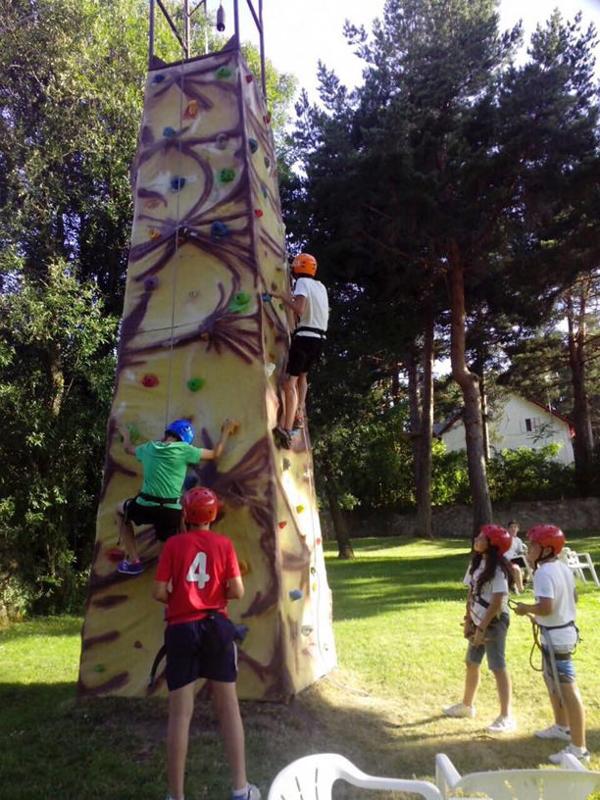 Grupo de niños haciendo escalada en el rocódromo del campamento de verano en Marbella