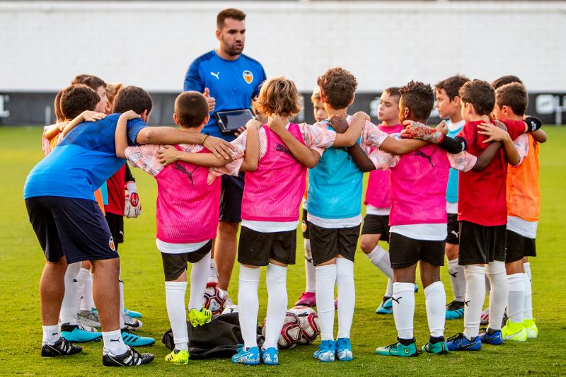 grupo de niños escuchando a su entrenador de fútbol en el campamento de fútbol