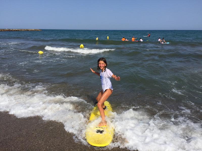 niña practicando surf en la playa durante el campamento de verano ingles zaragoza