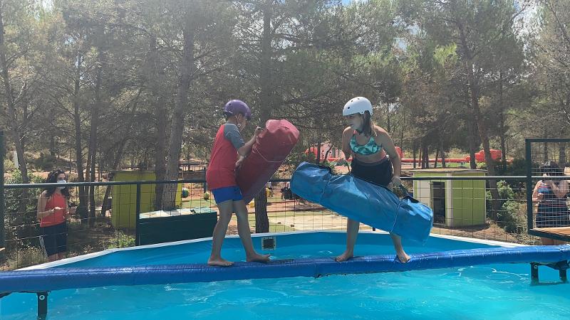 Dos niños con hinchables compitiendo en los juegos acuáticos de equilibrio en los campamentos de parkour
