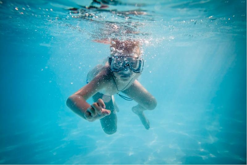 niño en una piscina buceando con unas gafas de snorkel debajo del agua en el campamento de verano multiactividades de Valencia