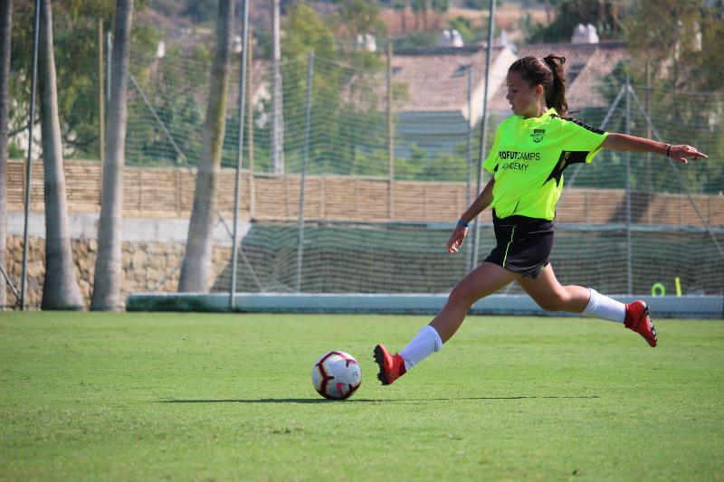 niña jugando al fútbol y mejorando su técnica en el campamento de verano de fútbol