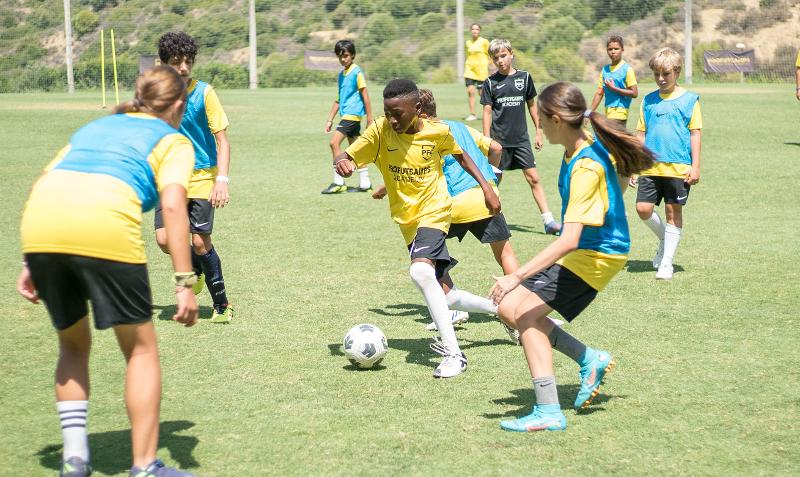 Chico esquivando a sus compañeros con el balón en el summer camp marbella