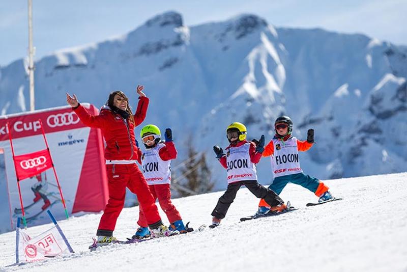 Participantes infantiles de las vacaciones ski aprendiendo sus primeros pasos sobre los esquís