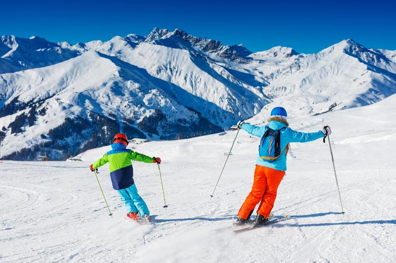 Participantes de las vacaciones ski descendiendo en esquís una montaña llena de nieve