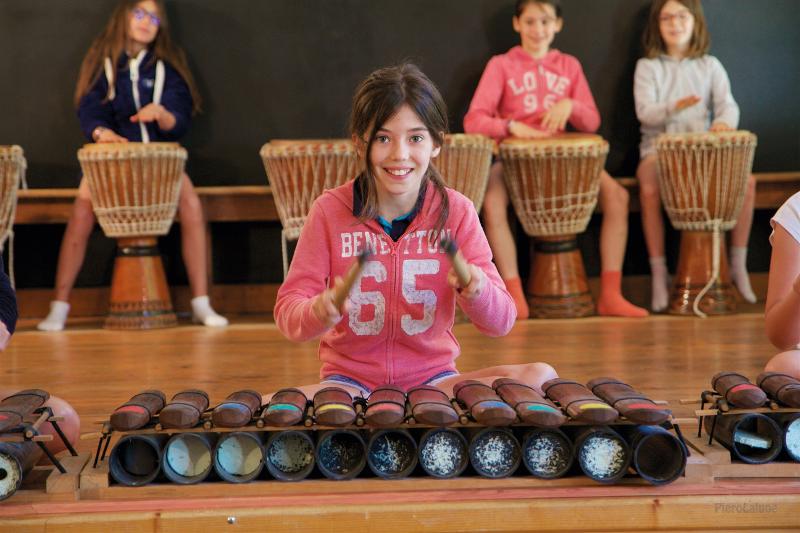 Participante del campamento de verano en Cazorla tocando un instrumento de percusión durante el recital de música final