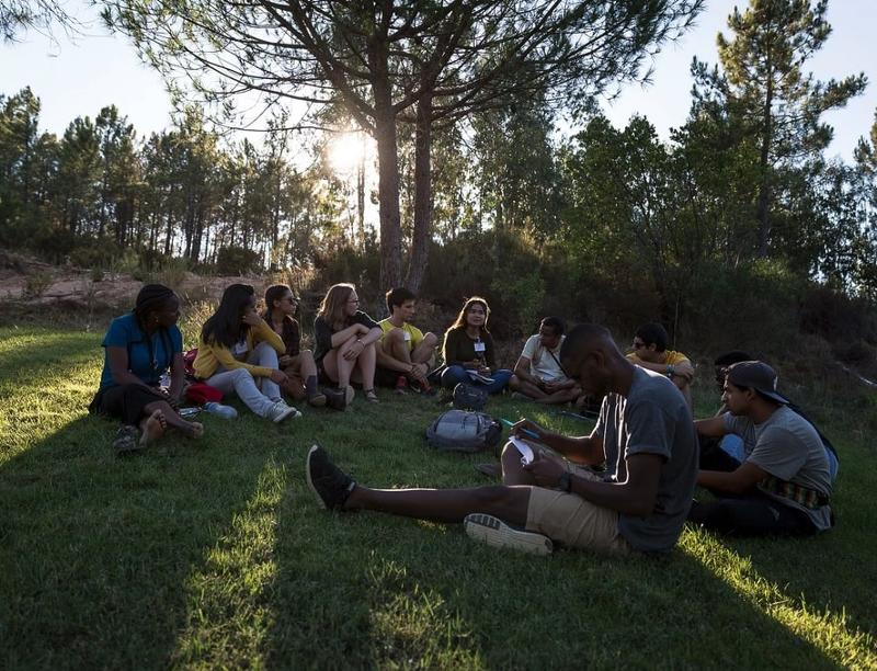 jovenes sentados disfrutando de la naturaleza y de sus compañeros del campamento de verano en portugal