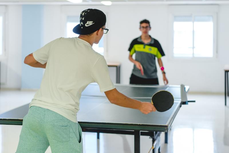 dos chicos jugando al pingpong en las instalaciones de la residencia del campamento de verano castilla y leon