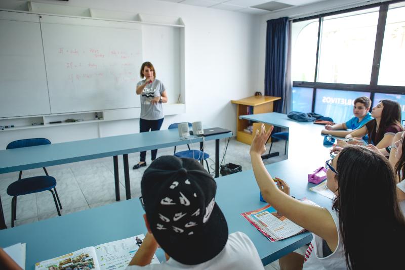 Niña levantando la mano en clase en el campamento de verano Alicante 