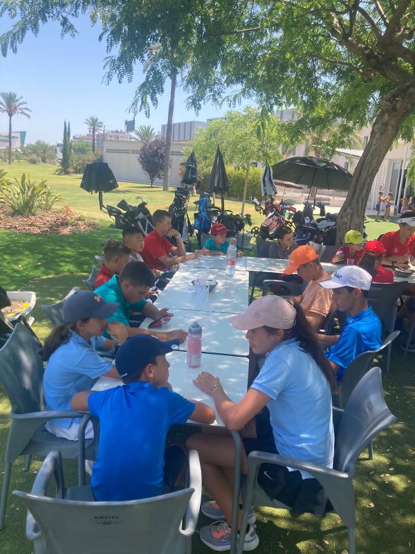 Niños sentados en una mesa después de jugar al golf en el campamento de verano Alicante
