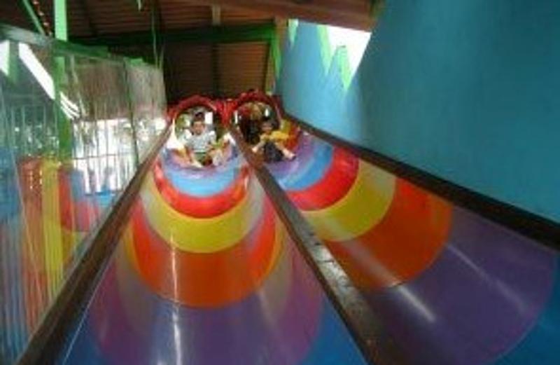 Dos niños tirándose por un tobogán de colores en uno de los juegos de campamento en Madrid