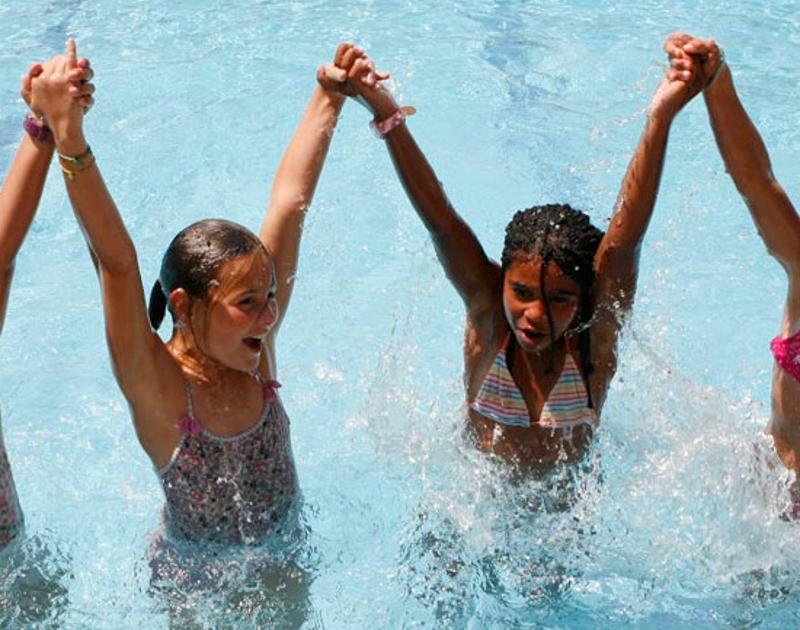 Grupo de niñas celebrando la victoria con las manos cogidas en la piscina del campamento de verano en Madrid