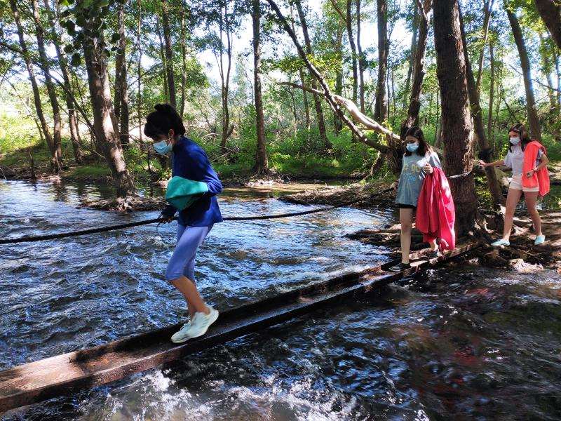 Niñas atravesado el embalse con un puente de metal en el campamento en la naturaleza de Madrid