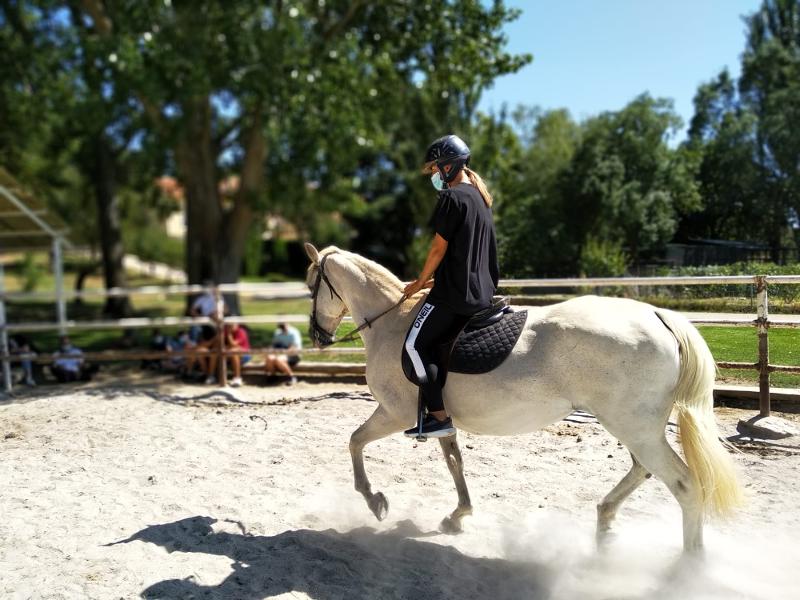 Joven montando a caballo en la clase de hípica del campamento con animales en Madrid