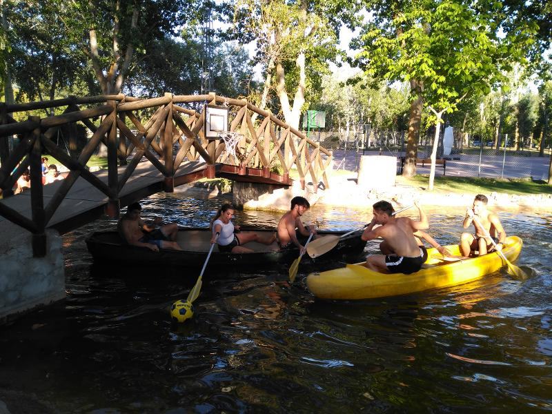 Jóvenes posando divertidos en las canoas mientras reman por el embalse en el campamento de verano en Madrid