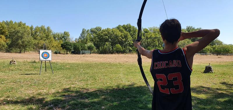 Niño apuntando a la diana en la sesión de tiro con arco del campamento de aventuras en Madrid