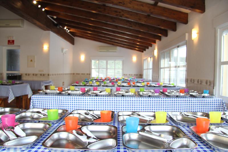 Comedor preparado con las bandejas para cada uno de los jóvenes participantes del campamento de verano en Madrid