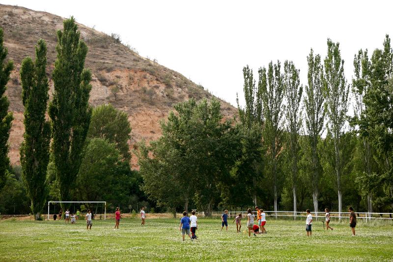 Grupo de jóvenes disfrutando de las actividades deportivas en el campo de fútbol al aire libre del campamento en Madrid