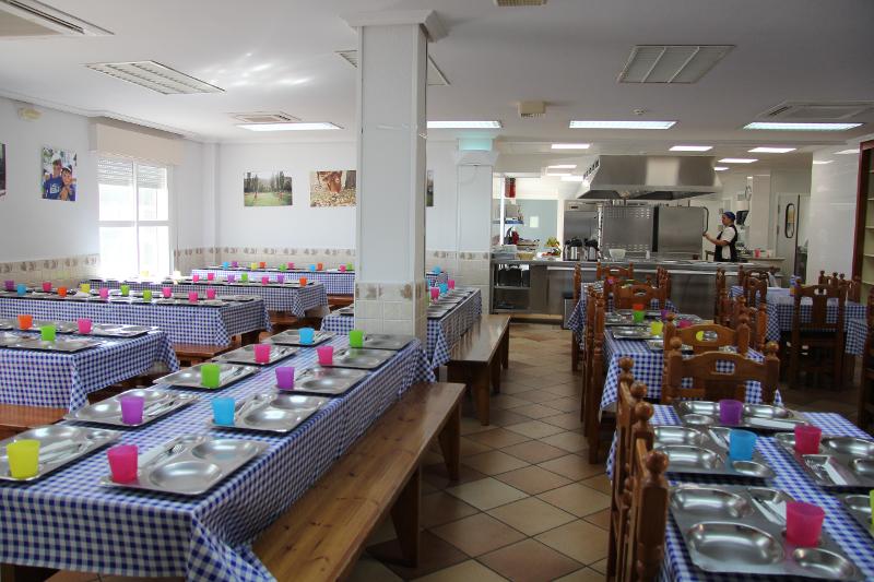 Comedor preparado con las bandejas en cada puesto para los jóvenes del campamento de verano en Madrid