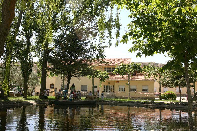 Grupo de niños remando la canoa en el embalse junto a la monitora del campamento de verano en Madrid
