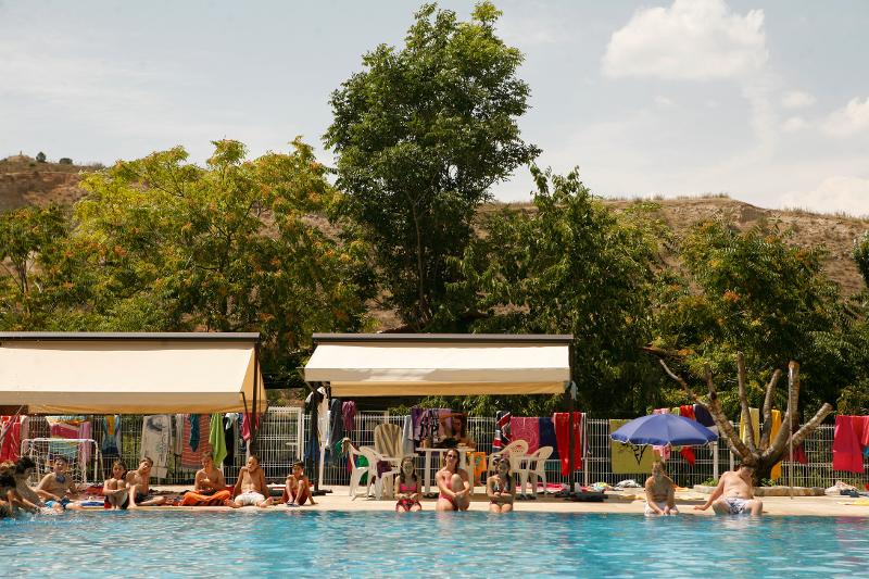 Grupo de niños sentados en el bordillo de la piscina en una tarde de actividades acuáticas del campamento de verano