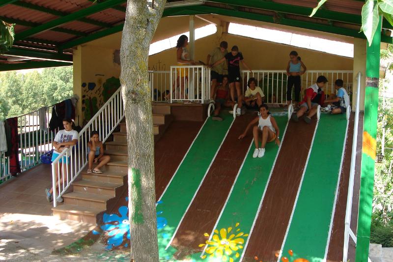 Niños deslizándose por los toboganes de exterior en el campamento de verano en Madrid