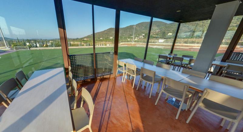 Zona de comedor con vistas a los campos de fútbol en el interior del campamento de verano en Valencia