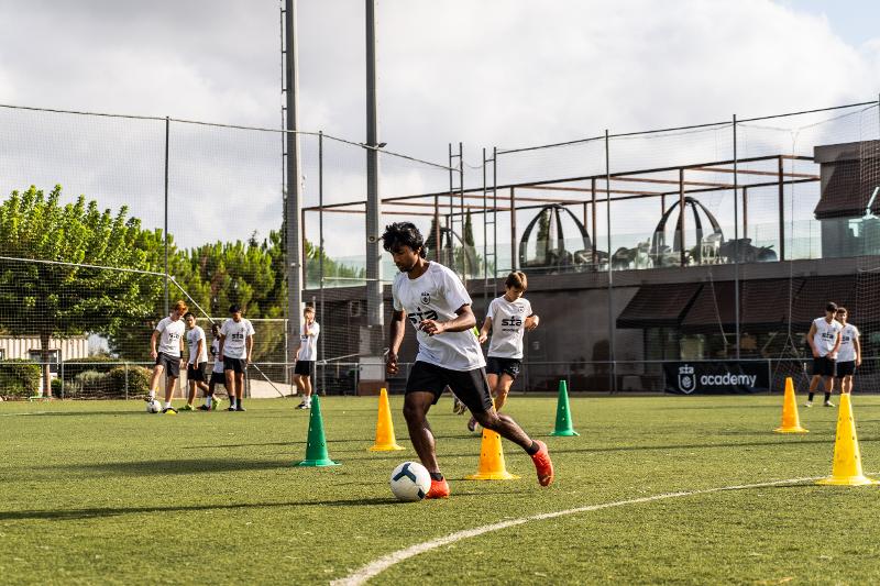 Adolescente entrenando con conos en un campamento de futbol
