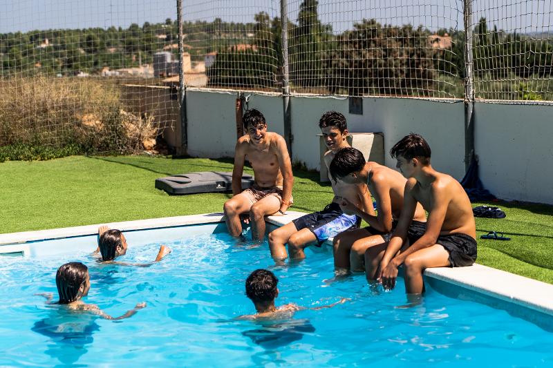 Grupo de jóvenes sentados en la piscina del campus de fútbol Valencia