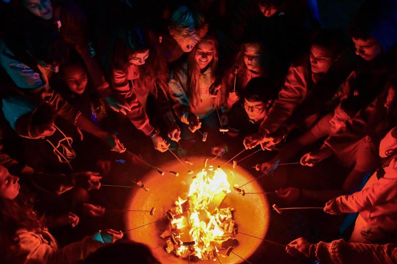 Grupo de jóvenes durante el campamento de Pamplona cenando alrededor del fuego