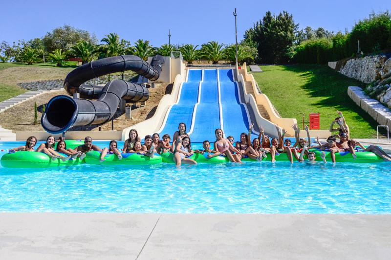 Grupo de jóvenes disfrutando del parque acuático en el campamento con piscina