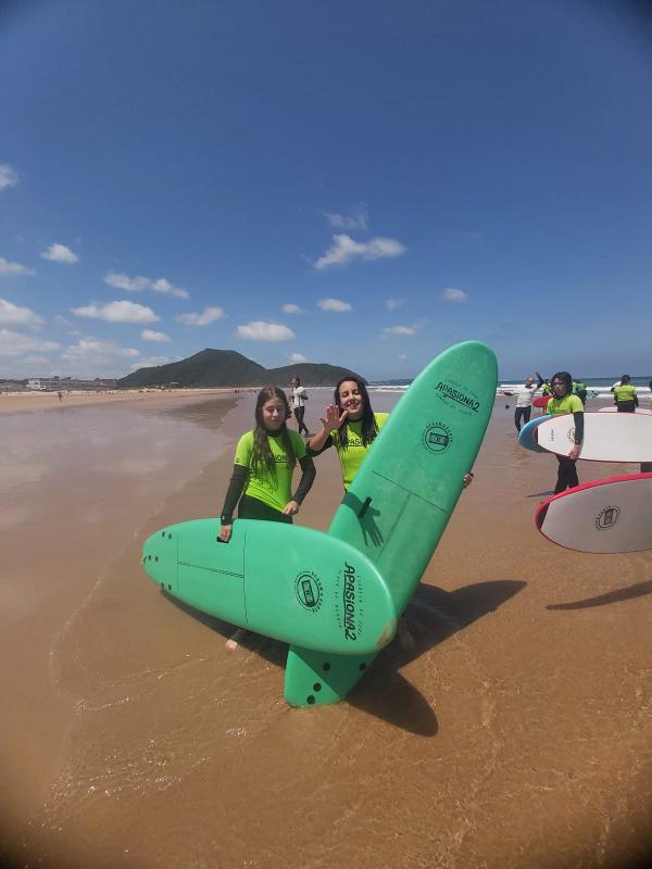 Niñas en una playa practicando surf durante un campamento con traslado Madrid