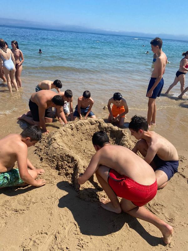 Groupe de jeunes faisant des châteaux dans le sable durant leur séjour linguistique anglais surf