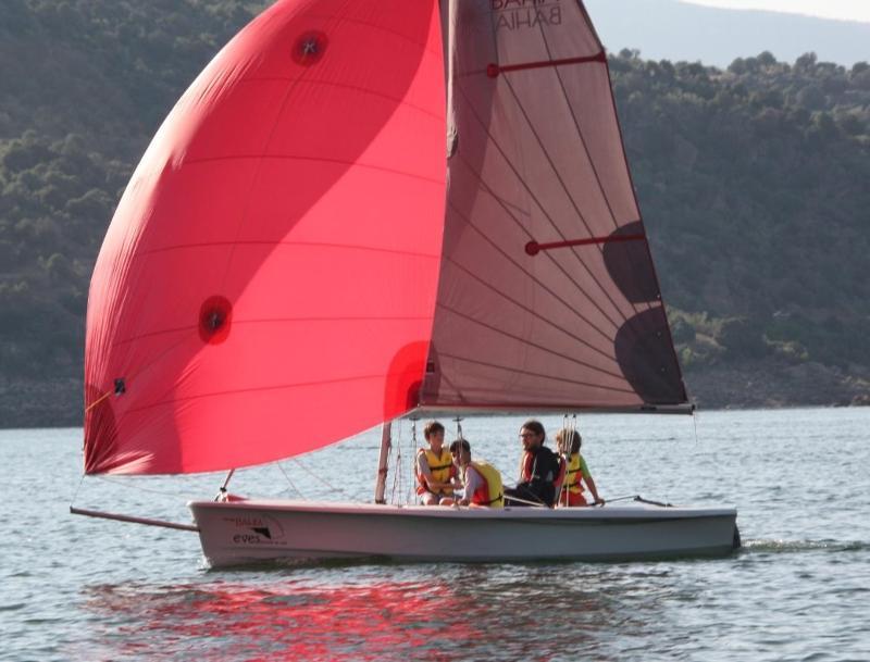 Tres niños montados en la vela con el monitor en el campamento madrid